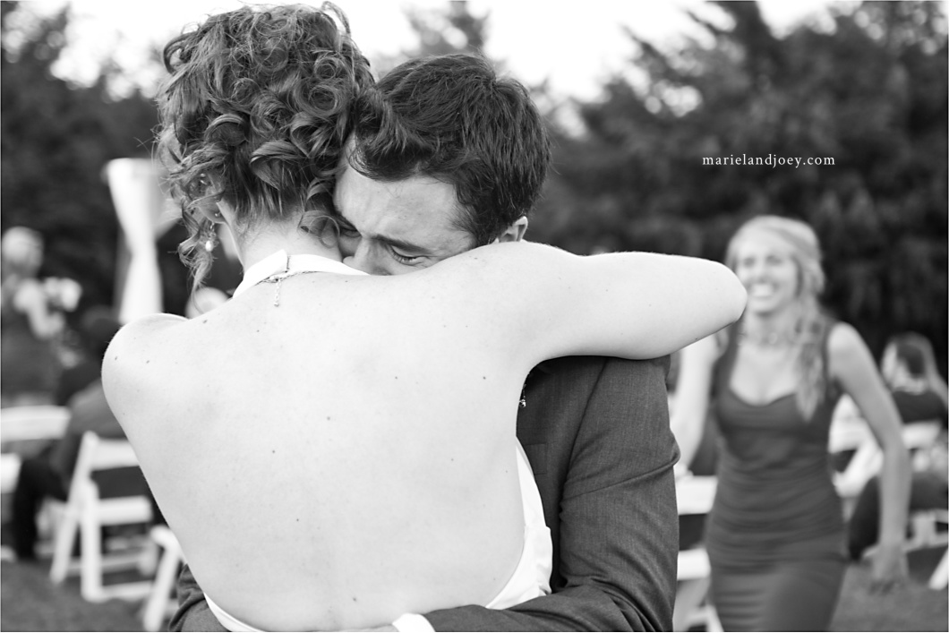 outdoor backyard wedding ceremony groom cries while hugging bride